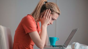Een foto van een vrouw met geldproblemen achter haar laptop