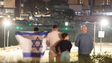2023-11-25 01:15:23 epa10993393 People with an Israeli flag looks on as an Israeli army helicopter carrying Israeli children hostages who were held by Hamas in Gaza, landed at the helipad of the Schneider-Children's Medical Center in Petah Tikva, Israel, 24 November 2023. Israel and Hamas agreed to a four-day ceasefire agreement, mediated by Qatar, the US, and Egypt, that came into effect at 05:00 AM GMT on 24 November, with 50 Israeli hostages, women and children, to be released by Hamas and 150 Palestinian women and children that were detained in Israeli prisons to be released in exchange. More than 14,000 Palestinians and at least 1,200 Israelis have been killed, according to the Gaza Government media office and the Israel Defense Forces (IDF), since Hamas militants launched an attack against Israel from the Gaza Strip on 07 October, and the Israeli operations in Gaza and the West Bank which followed it.  EPA/ABIR SULTAN