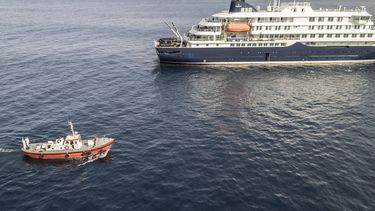 An aerial view of an ambulance boat carrying crew members wearing hazmat suits as they approach the pilot door on the starboard side of the cruise ship MV Hondius, while stationary off the port of Praia, the capital of Cape Verde, on May 5, 2026. Two seriously ill crew members on a cruise ship stricken by a deadly hantavirus outbreak will be evacuated via Cape Verde to the Netherlands, allowing the vessel to sail on to Spain's Canary Islands, the ship operator said Tuesday.
The MV Hondius has been at the centre of an international health scare since Saturday, when WHO was informed that the rare disease -- usually spread from infected rodents typically through urine, droppings and saliva -- was suspected of being behind the deaths of three of its passengers.
As others fell ill, passengers and crew have been in isolation after Cape Verde authorities barred the ship from docking, and as health authorities scrambled to find a port that would take the Hondius.
AFP