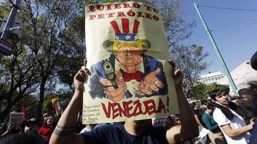 epa12624418 A person holds up a sign that reads 'I want your oil Venezuela' during a protest against the United States raid on Venezuela near the US Embassy in Mexico City, Mexico, 03 January 2026.  EPA/SASHENKA GUTIERREZ