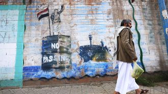 epa13232230 A person walks past the shuttered Saudi embassy with a graffitied wall depicting a Houthi fighter stopping a ship off the coast of Yemen, in Sana'a, Yemen, 11 September 2026.  Yemen's Houthi group said navigation in the Red Sea and Bab el-Mandeb Strait remained safe except for Saudi vessels, which it says remain subject to a blockade, after seizing the port city of Mocha on 10 September and making further gains around the strategic strait on 11 September.  EPA/YAHYA ARHAB