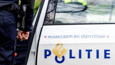 GRONINGEN - Een politieagent op straat naast een politieauto. ANP XTRA KOEN VAN WEEL