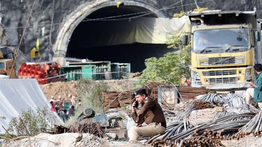 2023-11-25 16:47:09 epa10993940 An Indian policeman sits on construction material piled outside the mouth of a tunnel that collapsed on the Brahmakal Yamunotri National Highway in Uttarkashi, India, 25 November 2023. Rescue and relief operations were underway as 40 workers remained trapped after an under-construction tunnel collapsed on 12 November 2023. The workers were expected to be rescued on 24 November but the rescue work halted due to some technical glitch.  EPA/HARISH TYAGI