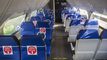 Een foto van een lege trein waar er bordjes op de stoelen aangeven of het wel of niet een zitplaats is.