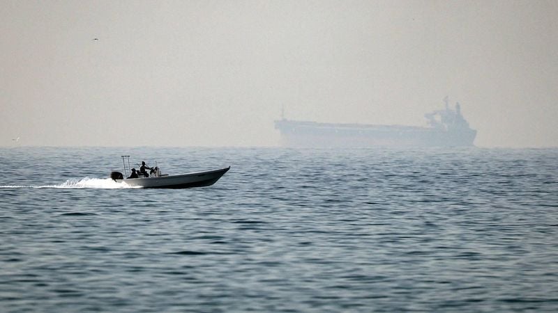 (FILES) A motorboat cruises along the shore off the town of Al Jeer on the Strait of Hormuz in the northern emirate of Ras Al Khaimah, with a tanker seen in the background, on February 25, 2026.
 The US president sent a peace plan to Iran as he voiced optimism on March 25, 2026 at ending nearly a month of warfare, with Tehran announcing that it will let 