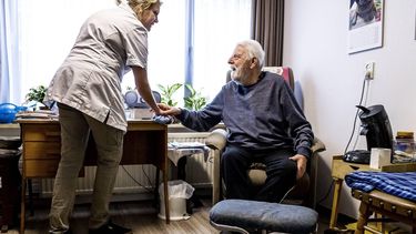 ILLUSTRATIE - Een medewerker van een verzorgingshuis helpt een bewoner. ANP REMKO DE WAAL