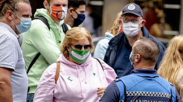Op deze foto zijn meerdere mensen in Rotterdam te zien met een mondkapje op, ze praten met een boa.
