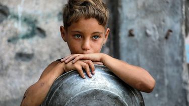 A boy waits with a pot to receive meals from a charity kitchen in Gaza City on July 14, 2025. 
Bashar TALEB / AFP