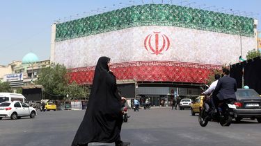 epa13035939 A veiled Iranian woman walks past a billboard featuring Iran's national flag at Enqelab Square in Tehran, Iran, 14 June 2026. US President Donald Trump saying on a social media platform that a deal could be signed soon.  EPA/ABEDIN TAHERKENAREH RESTRICTIONS: NO Access Israel Media/Persian Language TV Stations Outside Iran/Strictly No Access BBC Persian/VOA Persian/Manoto TV/Iran International TV. (As mandated by Iran's Directorate General for Foreign Media) --