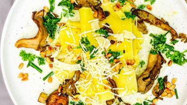 Op deze foto zie je open lasagne met paddenstoelen en groene kruiden
