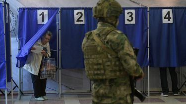 People vote in Russia's parliamentary election as a Russian serviceman secures a polling station in Donetsk, Russian-controlled Ukraine, on September 18, 2026, amid the ongoing Russian-Ukrainian conflict.  STRINGER / AFP