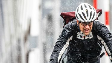 een foto van een fietsende man in de regen