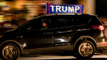 Een foto van een auto van een fan van Trump met een vlag