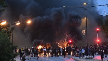 Op deze foto zijn de rellen in Malmo te zien, er hangt veel zwarte rook en er is vuur te zien.