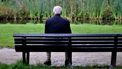Op deze foto zie je een eenzame oude man op een bankje in het park zitten.