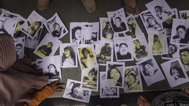 Mensen die op zoek zijn naar hun familieleden inspecteren foto's van slachtoffers van de voetbalramp in Indonesië
