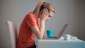 vrouw achter laptop is slachtoffer van pesten op het werk