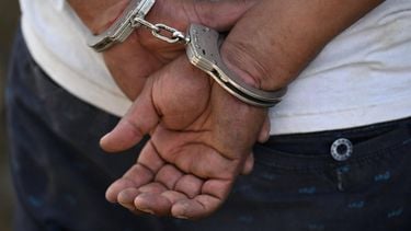 A man remains handcuffed after being detained by the police during an operation against gang members in Soyapango, El Salvador, on December 3, 2022.  Around 10,000 Salvadoran army troops and police officers surrounded the populous city of Soyapango, on the outskirts of capital San Salvador, as the government stepped up its fight against criminal gangs, President Nayib Bukele announced Saturday.
Marvin RECINOS / AFP