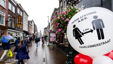 Een foto van een straat in Leiden met een waarschuwing om coronabesmettingen tegen te gaan