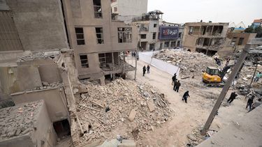 epa12821309 Iranians walk amid damaged residential buildings in southern Tehran, Iran, 15 March 2026. A joint Israeli and US military operation continues to target multiple locations across Iran since the early hours of 28 February 2026.  EPA/ABEDIN TAHERKENAREH