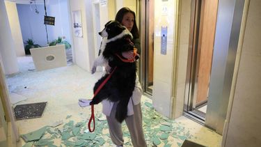 epaselect epa12845412 A woman carrying a dog leaves a damaged budling after an Iranian missile strike hit a residential area in Tel Aviv, Israel, 24 March 2026. The Israeli military reported that it had detected missiles launched from Iran, several of which struck central Israel.  EPA/ABIR SULTAN
