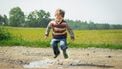 jongen springt in een plas water