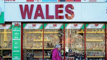 Een foto van een winkel en een wandelaarster met een mondkapje in Wales