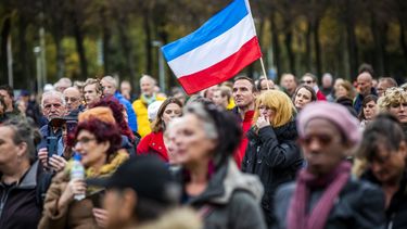 Op deze foto zijn betogers te zien, ze zwaaien met de Nederlandse vlag die ondersteboven is.