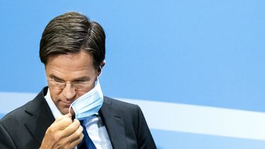 Een foto van premier Rutte die voor de persconferentie zijn mondkapje afzet