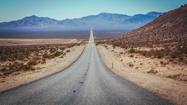 Op deze foto is Death Valley te zien, een lange autoweg met woestijn aan beide zijden.