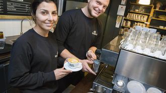Özge Kizilgöz, financieel medewerker, en Robin Scholten, koffiebrander, stralen achter de koffiemachine van Heilige Boontjes aan het Eendrachtsplein. / VINCENT VAN DORDRECHT
