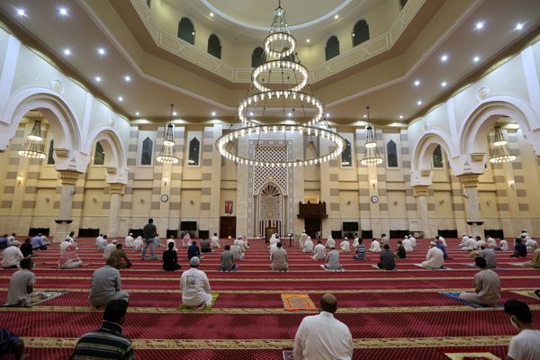 Een foto van een moskee in Mekka waarin mensen veilig afstand van elkaar houden