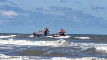 Een foto van twee reddingsboten op het water aan de kust
