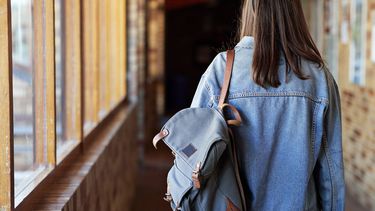 Een foto van een buitenlandse student die door een gang van een school loopt.