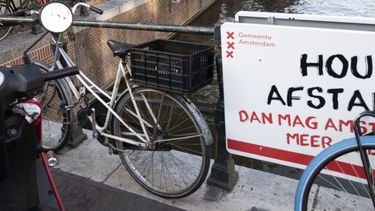 Een foto van een bord met de tekst houd afstand aan een Amsterdamse brug