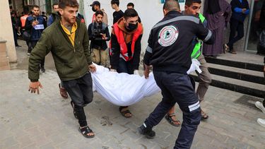 People carry the shrouded body of a person killed during Israeli bombardment at the Kuwait Hospital in Rafah in the southern Gaza Strip on December 20, 2023, amid ongoing battles between Israel and the Palestinian militant group Hamas. 
SAID KHATIB / AFP