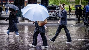 DEN HAAG - Mensen op straat trotseren regen en windstoten. Weerinstituut KNMI heeft voor delen van het land code geel afgegeven. ANP ROBIN UTRECHT