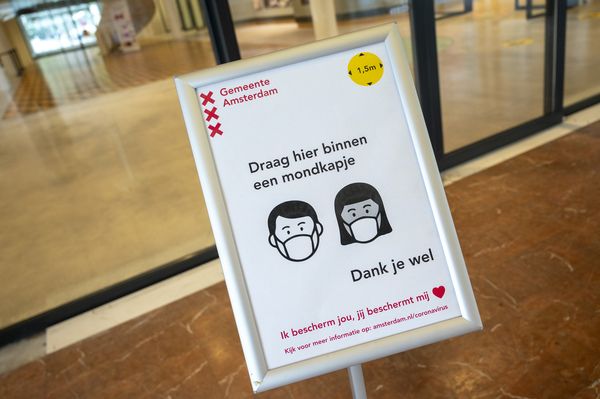 Een foto van een bord over het dragen van een mondkapje bij de gemeente Amsterdam