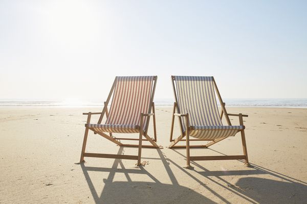 Op deze foto zie je twee strandstoelen op het strand staan