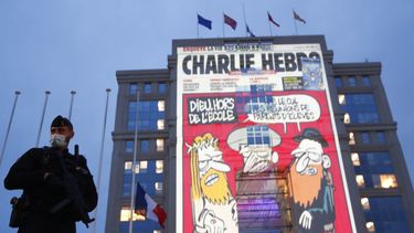 Op deze foto is een gebouw te zien waarop een cartoon van Charlie Hebdo op geprojecteerd is.
