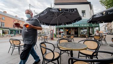 Een foto van een horecaman met mondkapje op een terras in Antwerpen