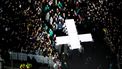 Een foto van een verlicht kruis dat door mensen richting het Passion-podium wordt getild.