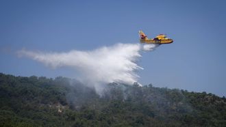 epa13085392 A firefighting plane drops water over a forest fire near a residential area in Calonge, Catalonia, Spain, 04 July 2026. A wildfire that broke out in the municipality of La Bisbal d'Emporda bosbrand is rapidly spreading, prompting authorities to order the lockdown of residents and tourists in Calonge and other nearby municipalities. EPA/DAVID BORRAT