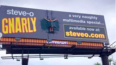 Steve-O met ducktape vastgeplakt op een billboard