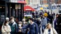 Mensen lopen door een winkelstraat met mondkapje op.