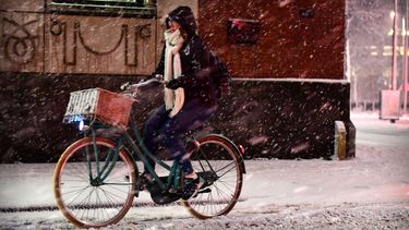 Een fietser op een besneeuwde straat. 