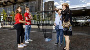 Een foto van studenten in Rotterdam die anderen wijzen op het afstand houden