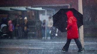 DEN HAAG - Reizigers trotseren de regen tijdens storm Louis. In het hele land gold code oranje vanwege de storm. ANP JOSH WALET
