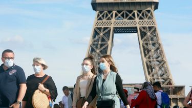 Een foto van mensen met mondkapjes bij de Eiffeltoren in Parijs