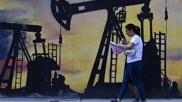 A woman walks past a mural depicting an oil pump on a street in Caracas on January 7, 2026. US Energy Secretary Chris Wright said in January 7, Washington will control sales of Venezuelan oil 